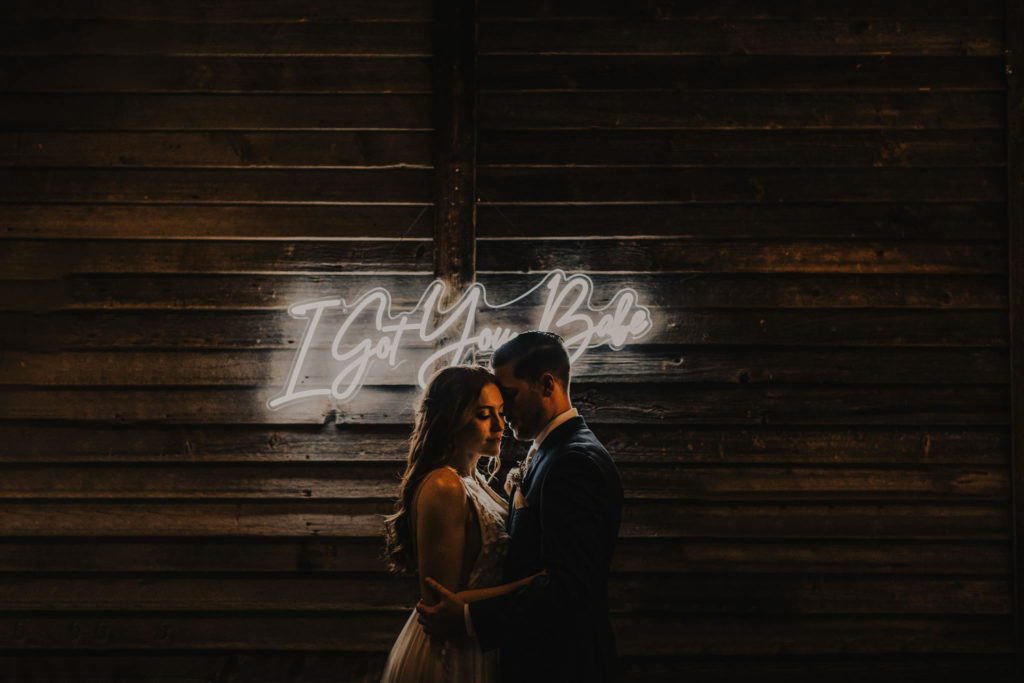 wedding day bride and groom in front of neon sign